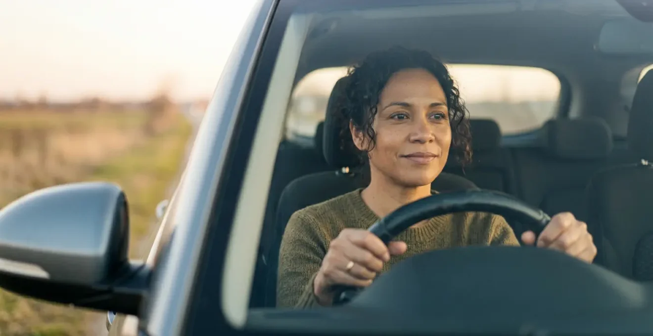 Conducteur au volant d'une voiture regardant vers l'avant avec une expression déterminée et optimiste symbolisant la recherche d'une nouvelle assurance