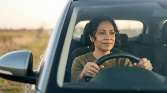 Conducteur au volant d'une voiture regardant vers l'avant avec une expression déterminée et optimiste symbolisant la recherche d'une nouvelle assurance