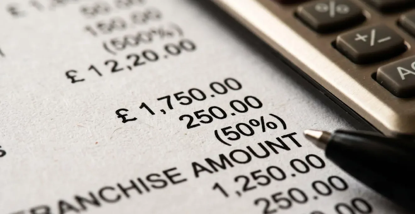 Vue macro sur un tableau de chiffres de franchise d'assurance automobile avec calculatrice et stylo